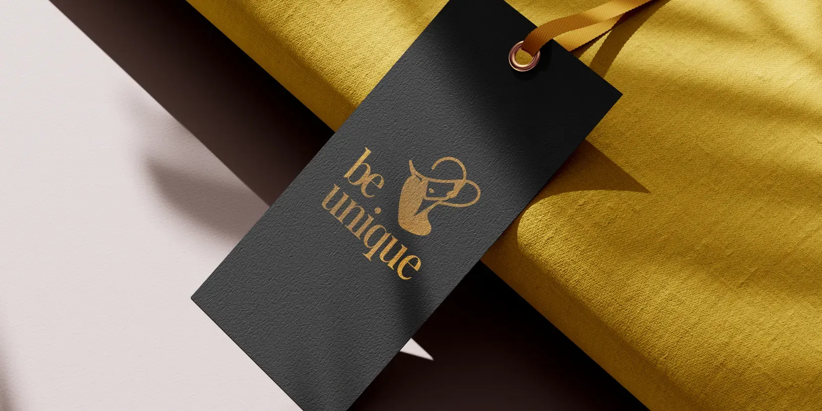 A black swing tag stamped in gold, on yellow fabric.