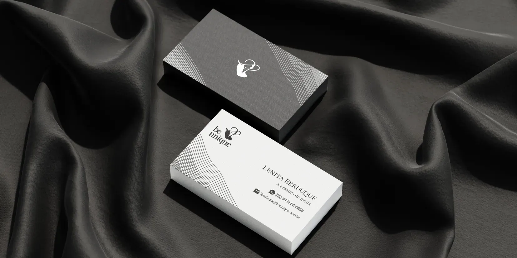 Business cards and a branded box arranged on black silk.