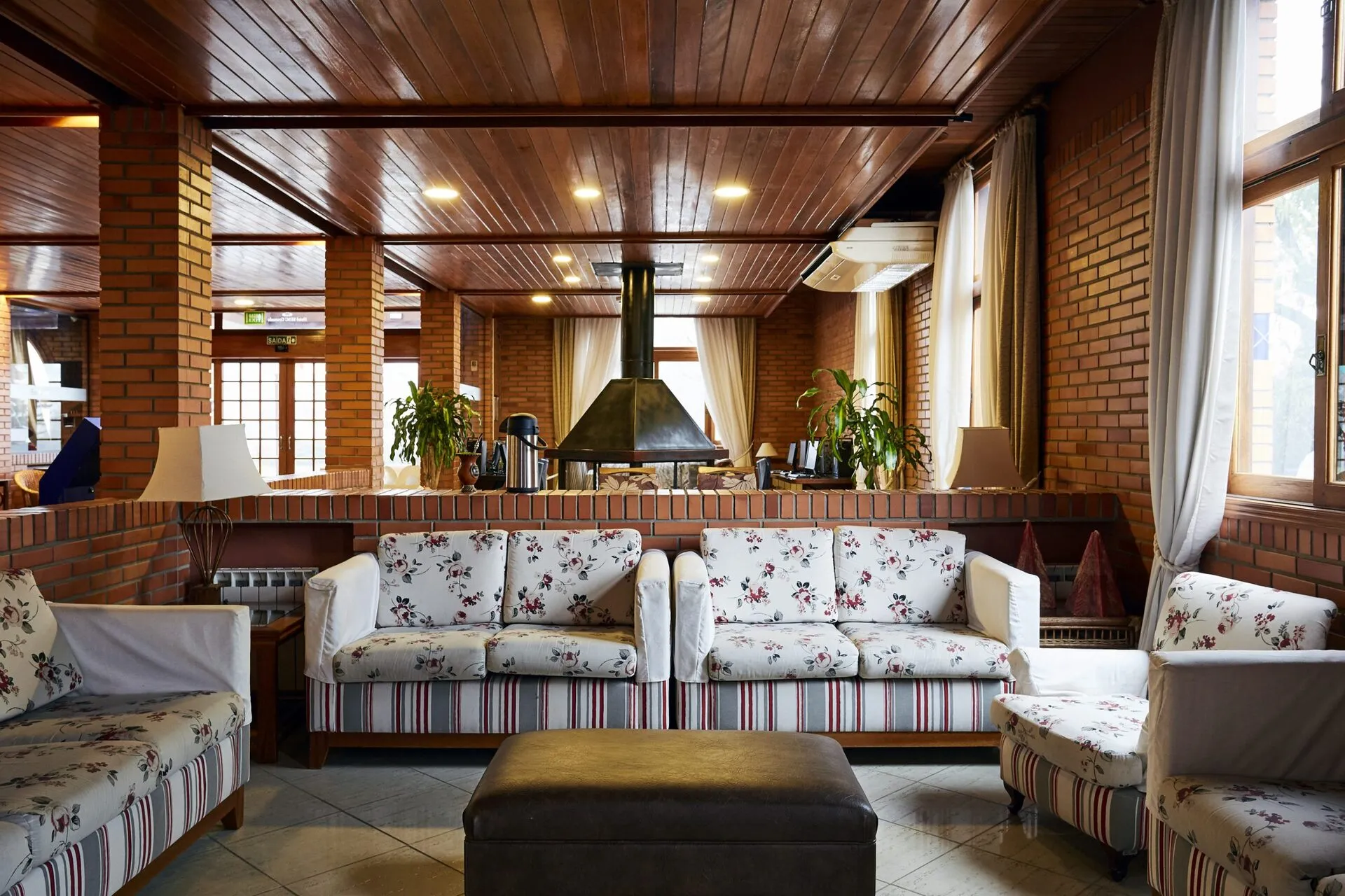 The hotel lounge: a stone fireplace, floral sofas and a timber ceiling.