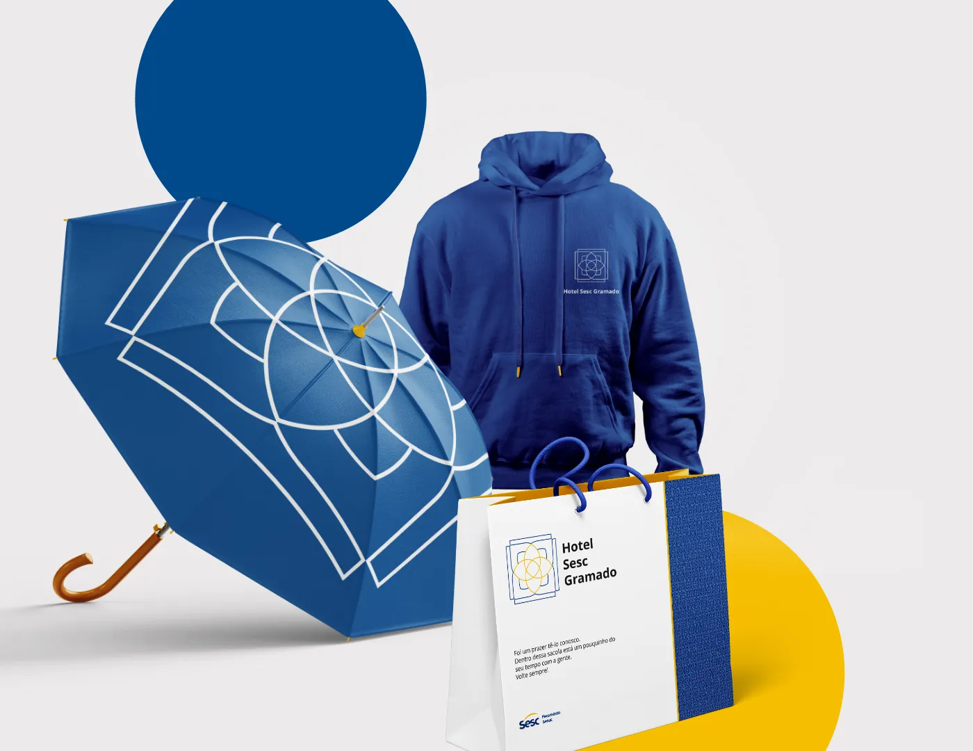 Branded merchandise: a navy umbrella and hoodie beside a Hotel Sesc Gramado paper bag.