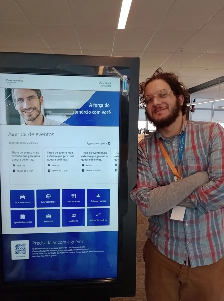 A man standing beside the lobby totem, which is showing the events agenda.